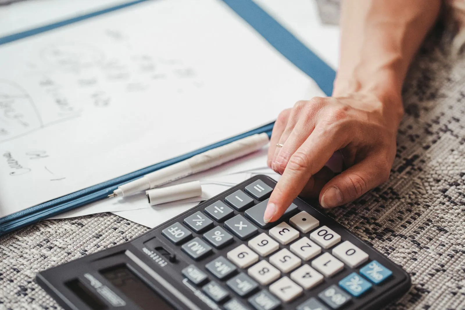 Hand calculating figures on financial documents